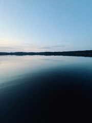 Peaceful evening lake reflection, sky and trees silhouettes on the lake surface, summer lake in the countryside