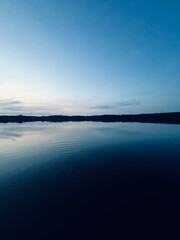 Peaceful evening lake reflection, sky and trees silhouettes on the lake surface, summer lake in the...