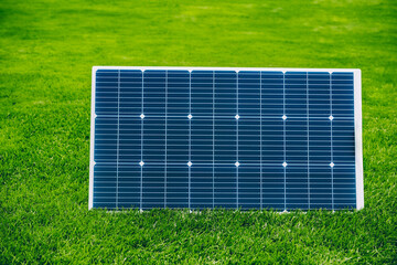 Solar panel generating renewable energy on green grass in a summer sunny day.