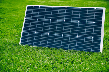 Solar panel generating renewable energy on green grass in a summer sunny day.