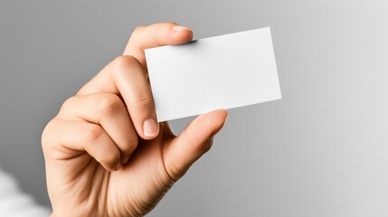 Obraz premium Hand holding blank rectangular card with simple gray background minimalist design