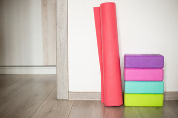 Colorful yoga mats and blocks arranged neatly in a home studio next to a light wooden floor