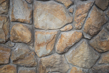 Natural stone wall with textured surface in warm earth tones adds character to the outdoor space in mid-afternoon light