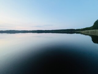 Peaceful evening lake reflection, sky and trees silhouettes on the lake surface, summer lake in the...
