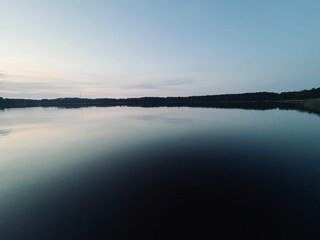 Peaceful evening lake reflection, sky and trees silhouettes on the lake surface, summer lake in the...