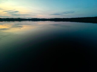 Peaceful evening lake reflection, sky and trees silhouettes on the lake surface, summer lake in the...