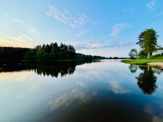 Peaceful evening lake reflection, sky and trees silhouettes on the lake surface, summer lake in the...
