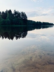 Peaceful evening lake reflection, sky and trees silhouettes on the lake surface, summer lake in the...