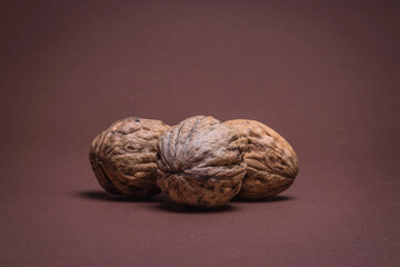 three Walnut walnuts on a dark brown background