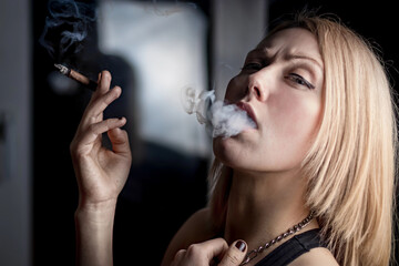 Beautiful girl smokes at night at the window