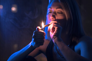 Obraz premium Beautiful blonde girl smokes a cigarette at a window in the Moonlight