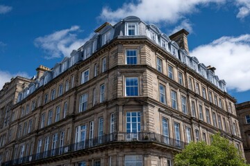 Fototapeta premium Stone building with multiple floors and windows under a blue sky with clouds