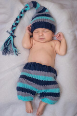 sleeping newborn dressed as a gnome baby on a white blanket