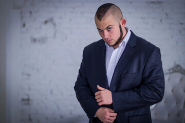 Strong man, bodyguard in a suit against the backdrop of the wall