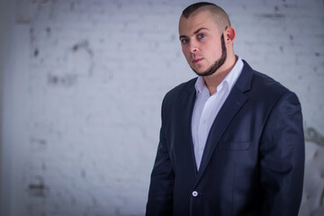 Strong man, bodyguard in a suit against the backdrop of the wall