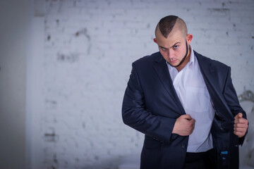 Strong man, bodyguard in a suit against the backdrop of the wall