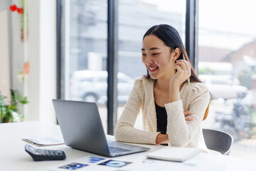 Happy businesswoman using laptop computer, working on marketing projects in bright modern office