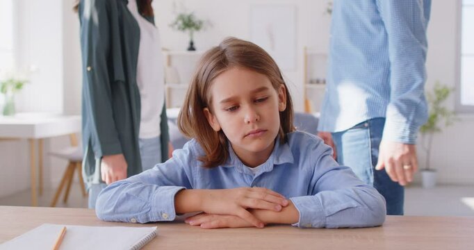 Family conflicts. Upset child suffers because of screams of parents who are quarreling with each other. Preteen boy covers his face with his hands as mom and dad have heated argument in background.