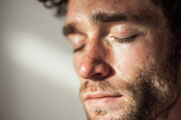 Fototapeta premium Close-up portrait of man with eyes closed inhaling deeply in soft natural light