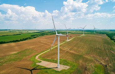 A row of large wind turbines stands tall in a vast, open field, showcasing renewable energy...