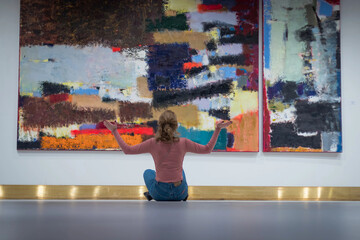 the girl sitting on floor and stares at the picture in the Gallery of modern art