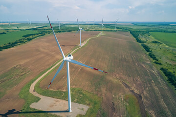 A row of large wind turbines stands tall in a vast, open field, showcasing renewable energy...