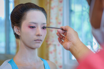 Beautiful Asian female tourist receives traditional Geisha or Maiko makeup, an ancient Japanese...