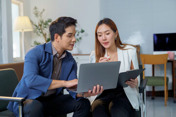 Two asian businesspeople working together using laptop and documents, discussing and sharing ideas...
