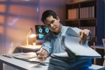 Businessman working late at night in office with a large pile of documents, struggling to meet deadline