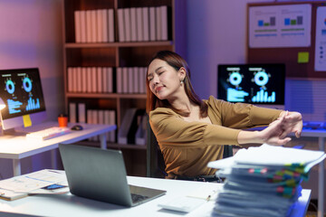 Young office worker stretching and relaxing muscles after long hours at the computer, finding relief from fatigue and stress at her desk