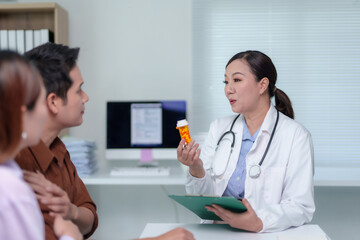 Female doctor discussing medication options with patients during a medical consultation in a hospital office, providing expert advice