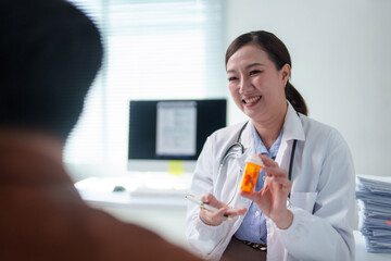 Female doctor holding medicine bottle explaining prescription to patient during medical consultation in hospital office