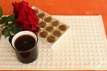 favorite chocolates, with a cup of coffee and a fragrant rose, a pleasant start to the day
