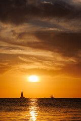 Sunset over the sea with sailing boats on the horizon