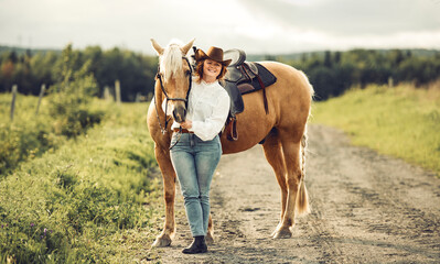 A woman, proudly wearing a cowboy hat, stands next to her horse