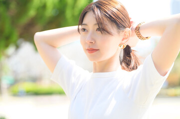 両腕を上げて髪を整える女性の真剣な眼差しと穏やかな表情