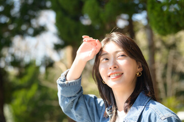 手をかざして日差しを避けながら微笑む女性の春の日常風景