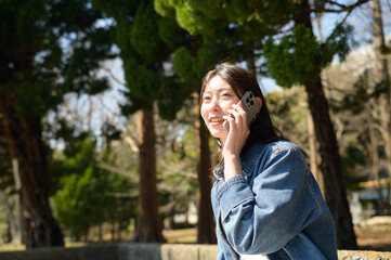笑いながら電話をする女性が春の陽気に包まれる公園で過ごす一コマ