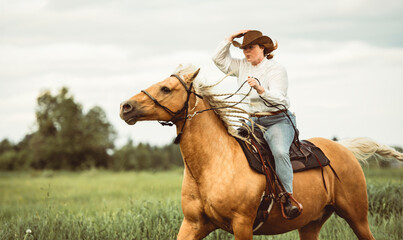 A woman is skillfully riding a horse gracefully in a lush field