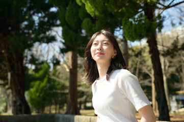 白いトップスを着た女性が自然の中で春の光を受けて見上げる姿
