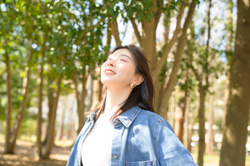 森林の中で大きく背伸びする女性が春の爽やかな空気を感じる瞬間