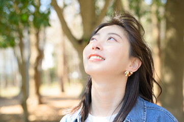 春の森林の中で空を見上げながら微笑む女性のポートレート