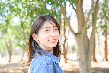 木漏れ日の中で微笑む女性が春の森林で自然を楽しむシーン