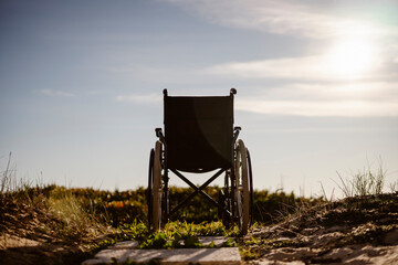 Empty wheelchair in the sun, near the ocean