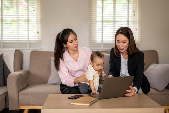 Three women are sitting on a couch, one of them holding a baby