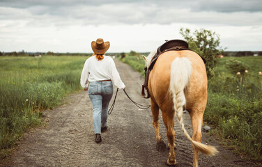 A woman is wearing a cowboy hat while riding a horse in an open field