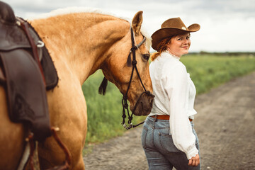 A woman is wearing a cowboy hat while riding a horse in an open field