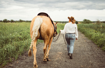 A woman is wearing a cowboy hat while riding a horse in an open field