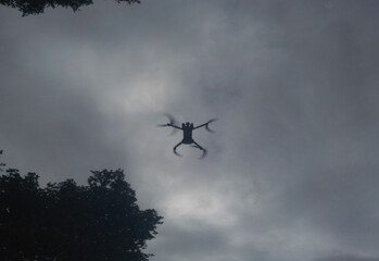 Reflection of a drone against a cloudy sky, surrounded by trees, at dusk, reflection of a drone