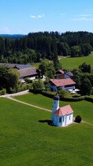 Charming Rural Landscape Featuring a Small Church Surrounded by Lush Greenery and Farms on a Sunny Day